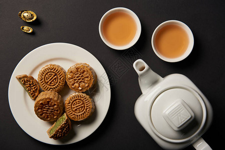 苏州月饼用黑色隔开的月饼杯子和茶壶的顶视图背景