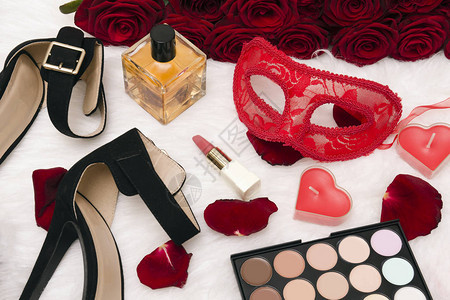 红色狂欢节面具一束红玫瑰黑色高跟鞋心形蜡烛口红香水瓶眼影和白色皮毛图片