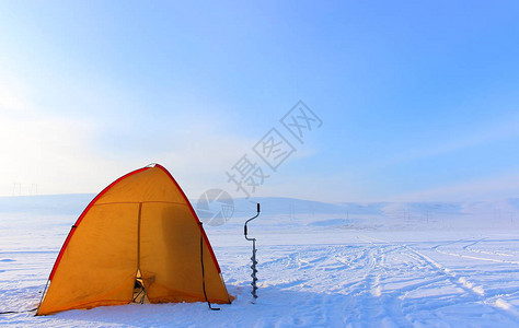 明亮的黄色旅游帐篷和在冰雪覆盖的空湖上进行冬季钓鱼的演习帮助渔民摆脱恶劣天气西伯利亚冬季的冰钓寒冷背景图片