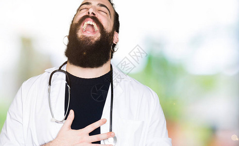 医用耗材长头发的医生穿着医用外套和听诊器因为有趣的疯狂笑话而大声笑着背景