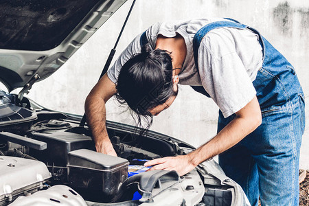 专业汽车机械师在汽车服务中统一固定汽车发动机和修理汽车引图片