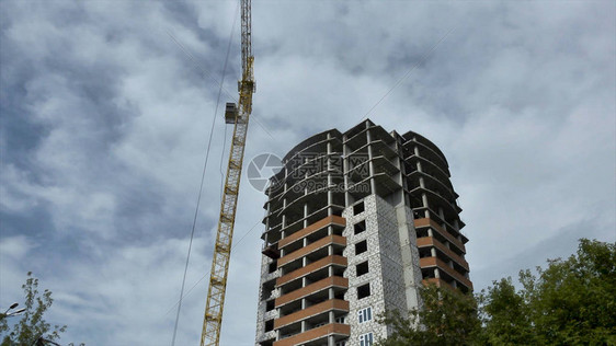 用起重机在的映衬下建造一座高层建筑底视图灰色多层建筑在施工过程中空图片