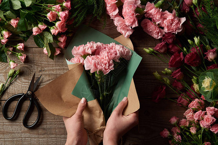 将美丽的鲜花包在木制表面的手工纸上的背景图片