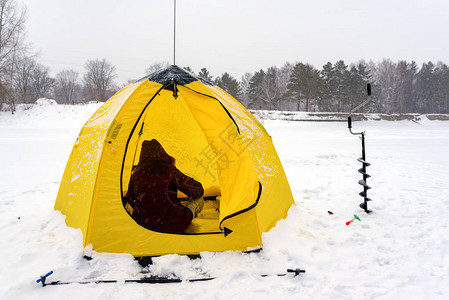 在俄罗斯雪和森林背景下坐在帐篷和冰螺中女孩角头的冬天图片
