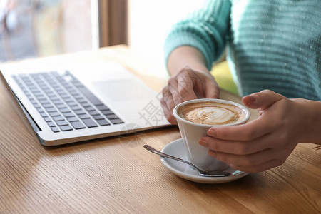 有笔记本电脑在咖啡馆喝咖啡的年轻图片