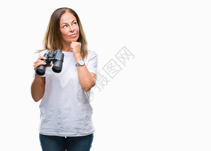 中年西班牙裔女透过双筒望远镜在孤立的背景下严肃地思考问题图片