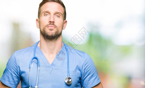 英俊的医生在与世隔绝的背景下穿着医疗制服双手合十图片