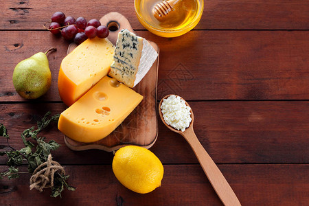木板上的硬奶酪蓝纹奶酪和干酪不同类型的奶酪和蜂蜜木制背景上乳制品梨柠檬和图片