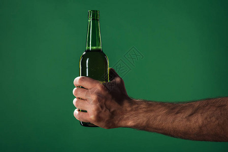 持有啤酒瓶的男子在绿色圣节日概背景图片