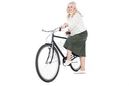 快乐的高级女骑着单车在背景图片