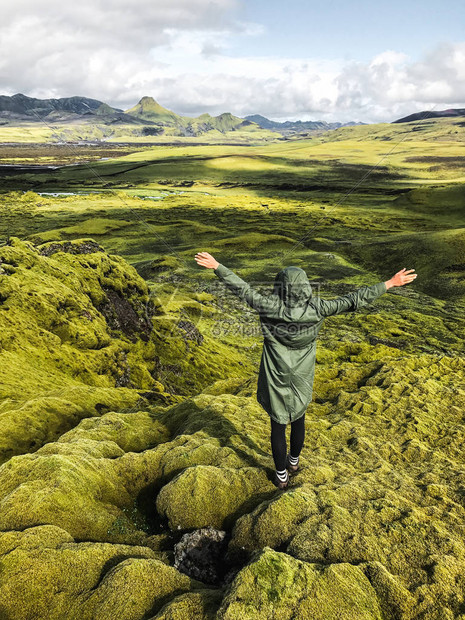 年轻的和平女人在冰岛欣赏苔藓覆盖的草地北极圈野生自然人与自然的联系穿着舒适防水绿图片