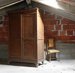 古老的木衣柜和破碎的椅子在灰尘弥漫的阁楼用图片