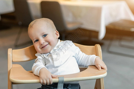 穿着白色马球t恤的可爱小男孩坐在木制婴儿椅上图片