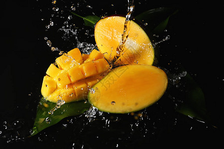 在深色背景上溅水的成熟芒果背景图片
