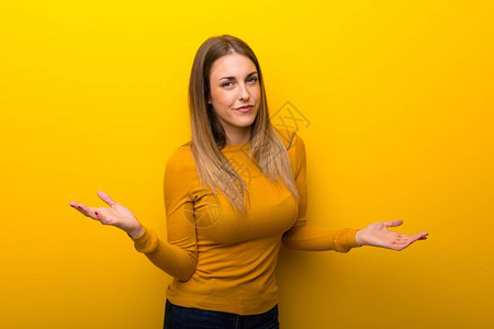 黄色背景的年轻女因不懂而感到不快乐和沮丧图片