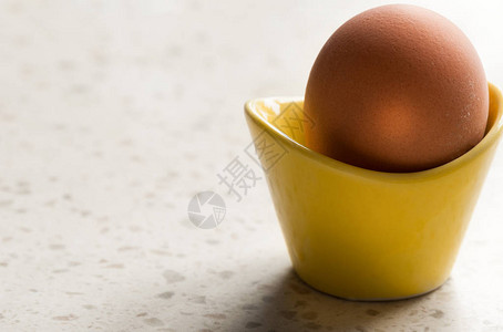 黄色鸡蛋杯中煮熟的棕色鸡蛋图片