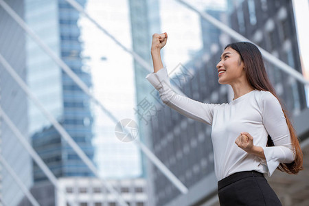 妇女举起手来争取商业赢家成功的概念图片