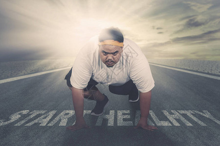 照片上一位肥胖男子在路上跪在健康开始的文字之上时准备奔跑图片