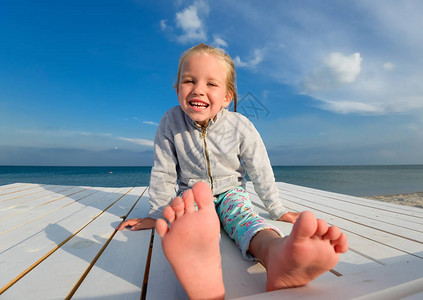 夏天海滩的小俏丽的女孩开朗的小女孩在蓝天和夏日大海的背景下笑着快乐的小女孩在沙滩上玩背景图片