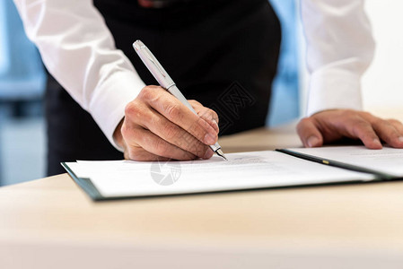 站在办公桌的商人与墨笔签了一份报告或合同图片