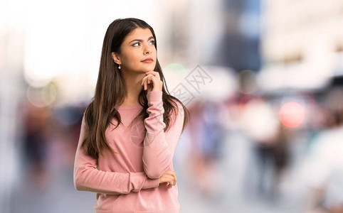 穿粉红衬衫的少女看着街边手图片