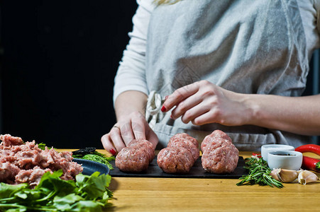 一名女厨师用生肉制备瑞典肉丸黑背景背景图片