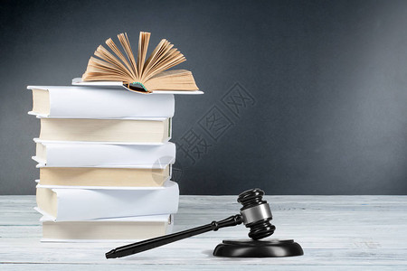 法律概念在蓝色背景的法庭或执法办公室的桌子上放着木制法官木槌的开放法律书籍背景图片