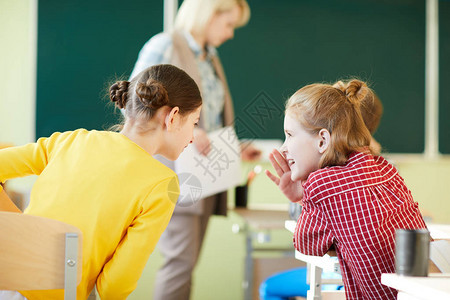 快乐积极的女学生坐在课桌前一边聊天一边在课堂上闲聊图片