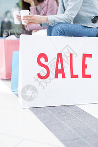 大型当代购物中心地板上的白纸袋上的红色销售通知和两个背图片