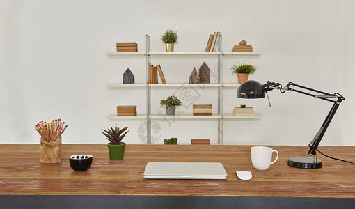 笔记本电脑和平板电脑在木桌和办公室内部与辅助书咖啡和植图片