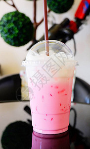 草莓奶粉色奶昔塑料杯中的冰粉色鲜奶和桌上图片