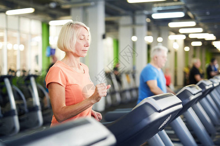 在当代体育中心或健身场的一部运动机上参加活跃服装锻炼的图片