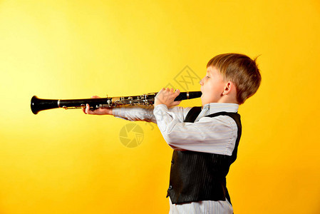 一个穿西装的小男孩吹奏单簧管图片