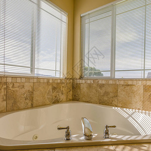 阳光明媚的浴室内的喷射浴缸一个心形的喷射浴缸巧妙地放置在浴室的角落阳光透过带白色百叶窗的大背景图片
