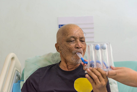70多岁的亚洲老人患者使用激励肺活量计或TriballTri流量计是帮助患者改善ICU病床上肺部功能的医疗设备图片