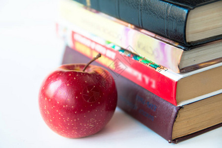 红色成熟多汁苹果接近书本在白桌图片