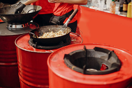 亚洲街头美食节在城市厨师在火锅里煮面条和蔬菜明火炒中式日本图片
