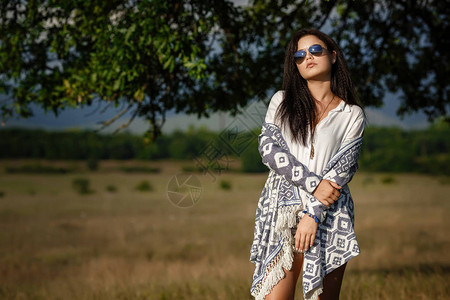 自由安心的概念有魅力的年轻女人在背景中有树的田野里散步她带着淡图片