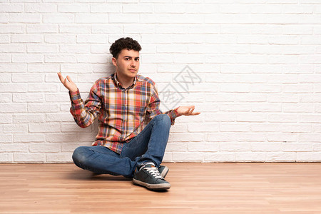 坐在地板上的年轻人因为不明白一些事情而不快乐图片