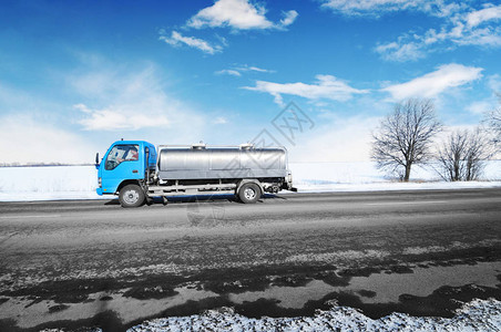 小型蓝色卡车在冬季农村公路上运送牛奶图片