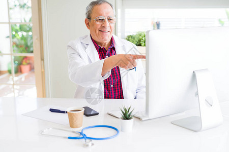 在诊所用笔记本电脑寻找解药的英俊高级医生以手和指着非常快乐的图片