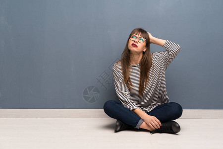 戴眼镜坐在地上的女人在抓头时图片