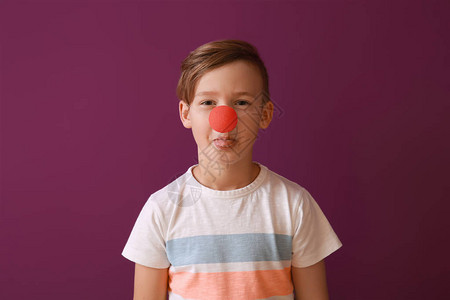 小丑鼻子沾着颜色背景的滑稽小男孩四月愚图片