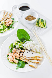 均衡的健康食品一碗玻璃面豆类鸡胸肉菠菜芝麻菜和黄瓜白色背景图片