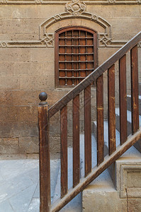 木窗和带木栏杆的楼梯通往埃及老开罗的历史悠久的贝特埃尔塞瓦拉建筑图片
