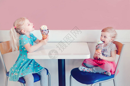 两个快乐的高加索可爱有趣的儿童女孩坐在一起吹牛嘘他们的冰淇淋的生活方式肖像爱嫉妒姐妹情谊美味可图片