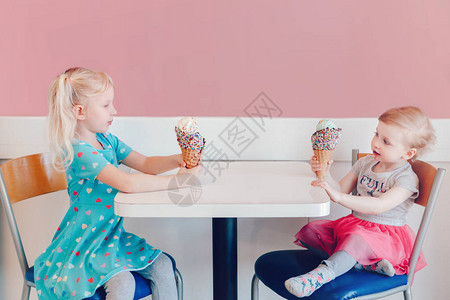 两个快乐的高加索可爱有趣的儿童女孩坐在一起吹牛嘘他们的冰淇淋的生活方式肖像爱嫉妒姐妹情谊美味可图片