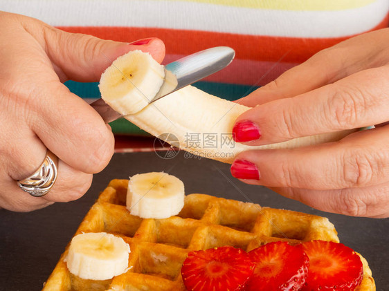 一个红指甲的女人切草莓和香蕉然后放在比利时的华图片