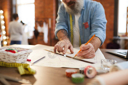 当代服装设计师在纸上用尺子和铅笔画时图片