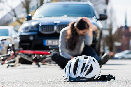 一名悲伤的年轻女子骑自行车与一辆四轮驱动汽车在城市发生意外碰撞后图片